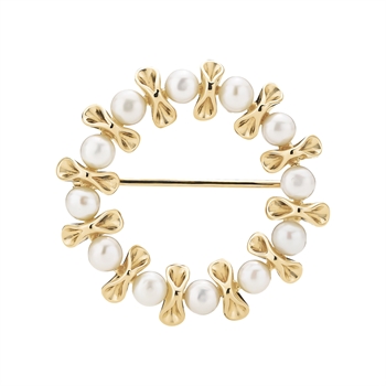 Circular brooch with alternating white pearls and gold bow shapes, featuring a pin on the back.