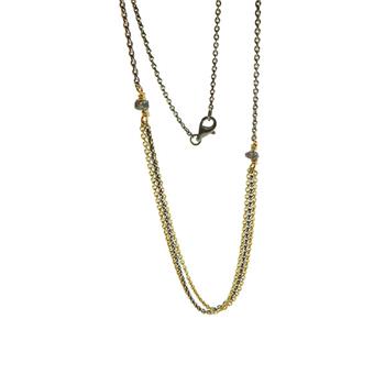 Multi-strand necklace with gold-plated and rhodium chains, raw diamonds, and clasp closure.