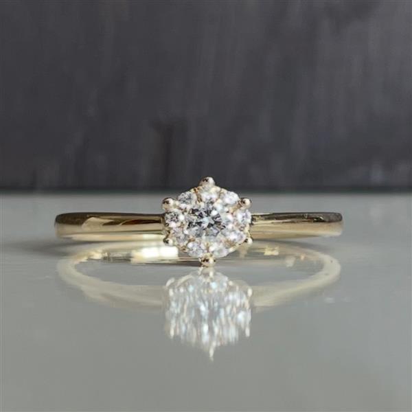 Gold ring with a star-shaped diamond setting, reflecting elegantly on a smooth surface.