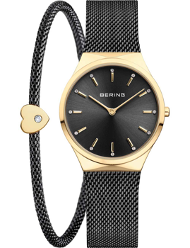 Bering watch with black dial, gold markers, mesh band, and bracelet with heart charm and stone.