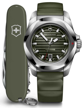 Green dial Victorinox watch with luminescent hands, hexagonal bezel, date at 6, next to a Swiss Army knife.